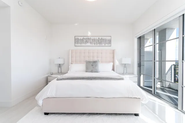 a bedroom with a white bed and a large mirror