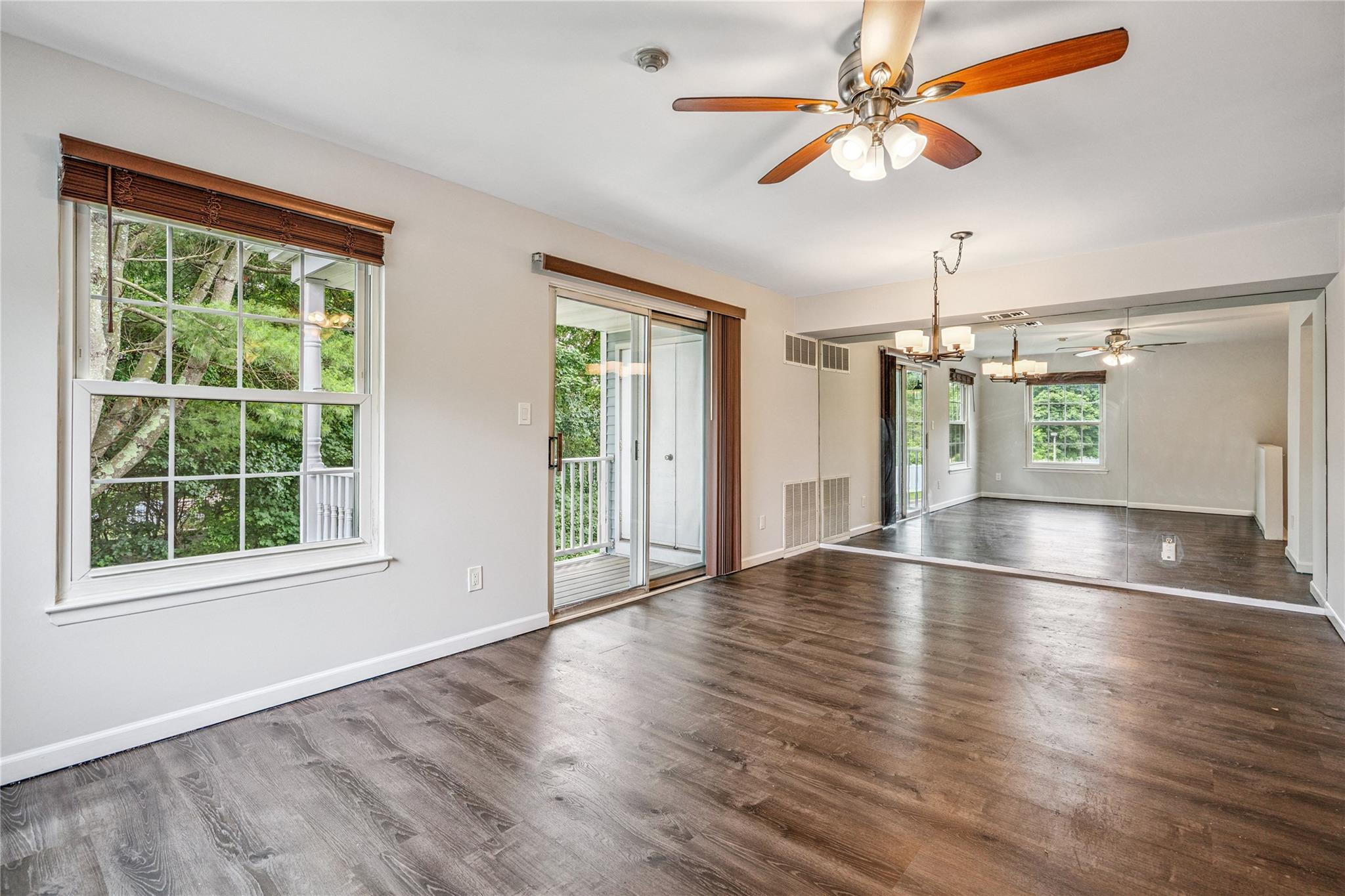 Empty room with a chandelier, a ceiling fan, and wood finished floors