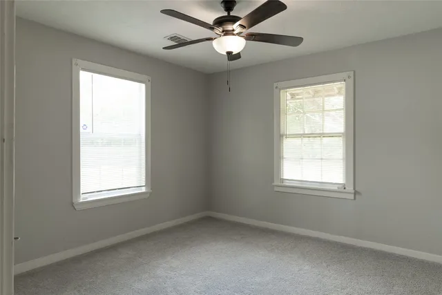 an empty room with a window and a fan