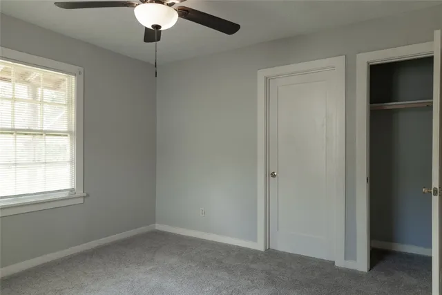 an empty room with a window and a chandelier fan