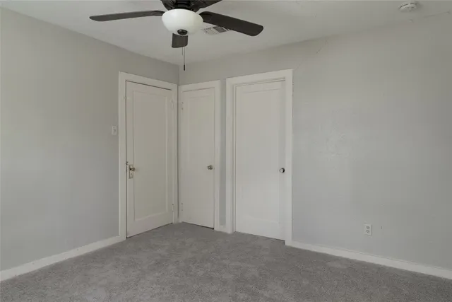 an empty room with a chandelier fan and closet