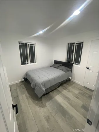 a bedroom with a bed wooden floor and mirror