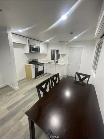 a kitchen with stainless steel appliances a dining table chairs wooden floors and a view of living room