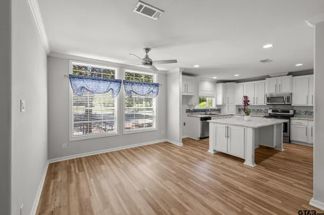 a kitchen with granite countertop a stove top oven a sink and white cabinets