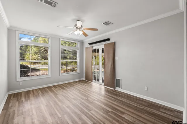 a view of an empty room with wooden floor and a window