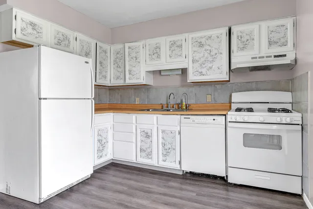 a kitchen with cabinets appliances and wooden floor