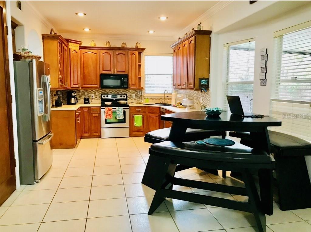 5219 Mystic Point Court Orlando, FL 32812 - Photo 6 of 13 a kitchen with stainless steel appliances kitchen island granite countertop a sink dishwasher stove and refrigerator with wooden cabinets