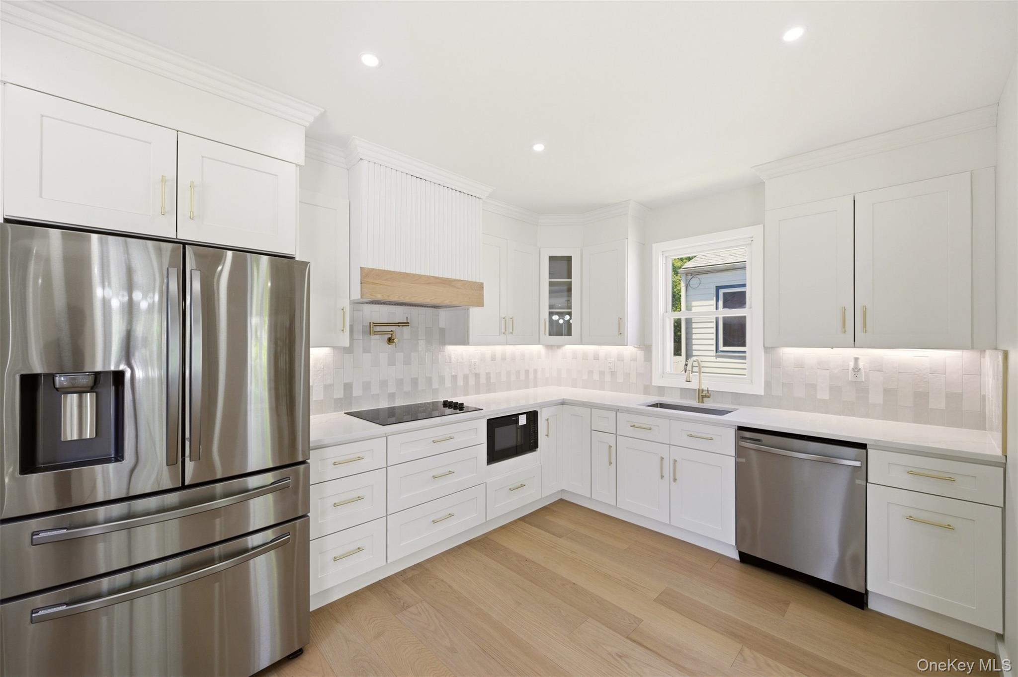 135 Whaley Street Freeport, NY 11520 - Photo 18 of 38 a kitchen with white cabinets and stainless steel appliances