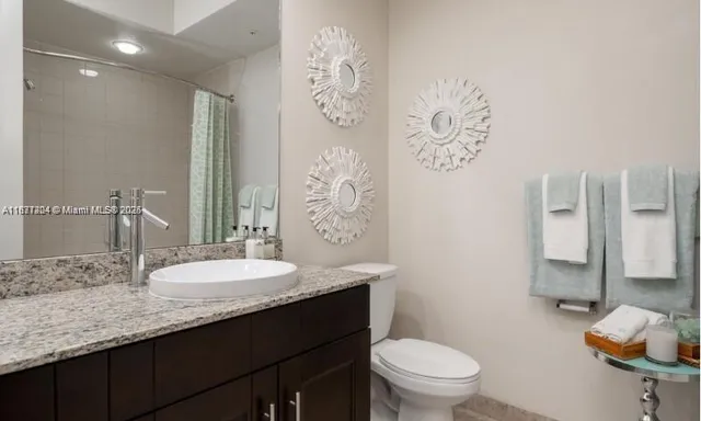 a bathroom with a granite countertop sink mirror vanity and toilet