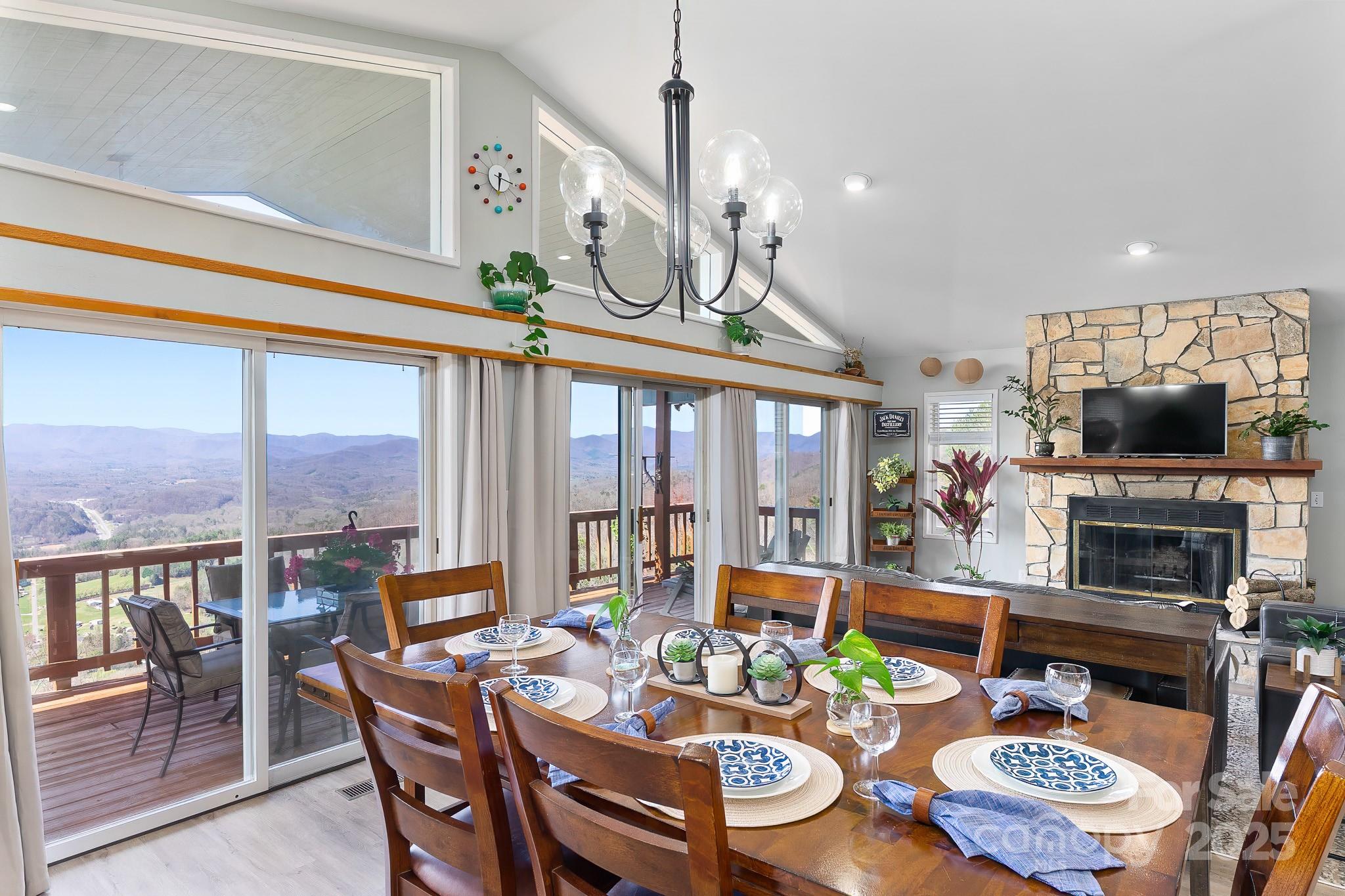 727 Chinquapin Mountain Road Franklin, NC 28734 - Photo 12 of 47 a view of a dining room with furniture large windows a flat screen tv and a chandelier