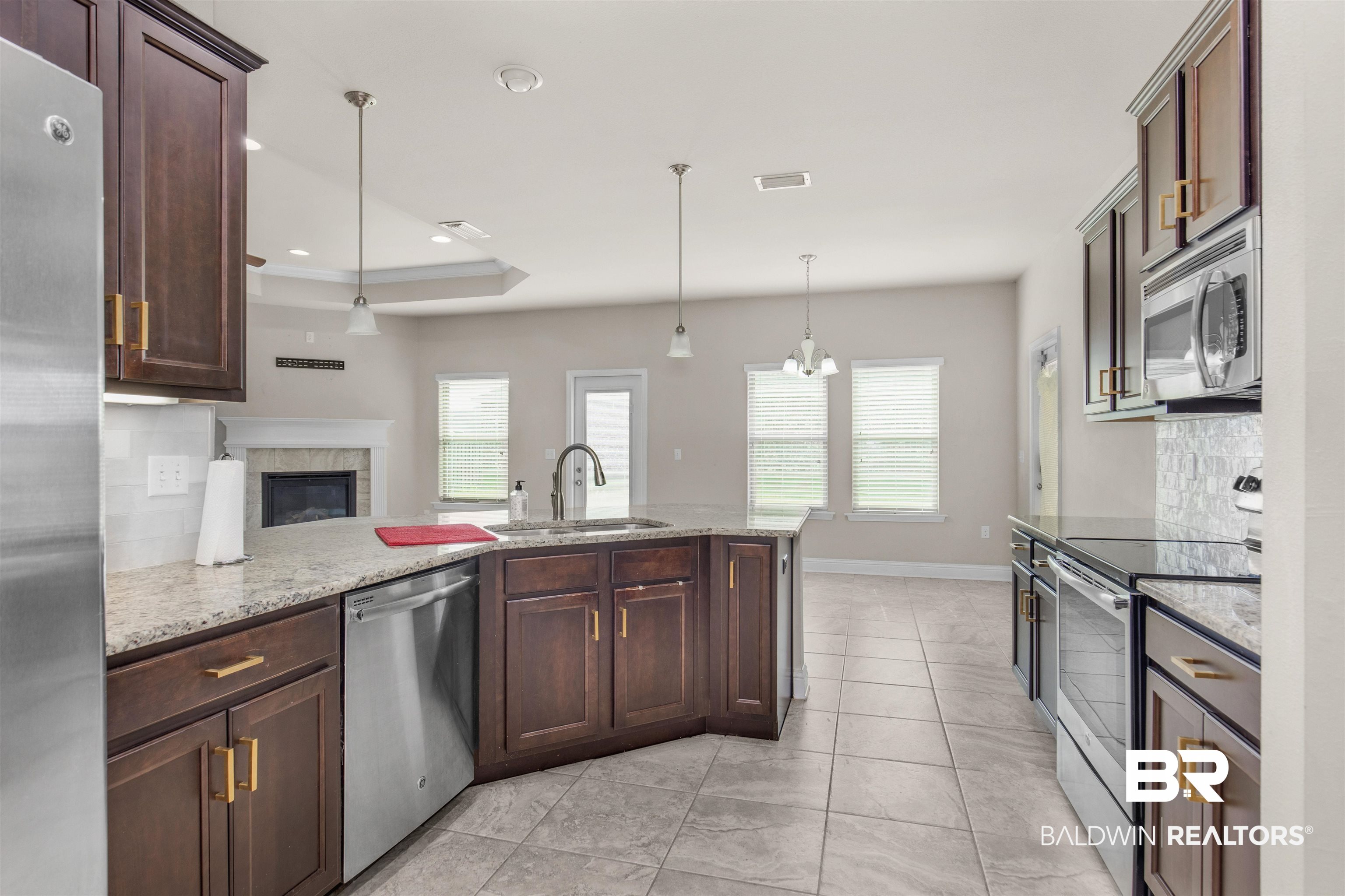122 Open Field Drive Fairhope, AL 36532 - Photo 7 of 27 Kitchen with a tray ceiling, light stone countertops, hanging light fixtures, appliances with stainless steel finishes, and sink
