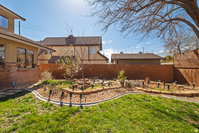 892 Cambridge Drive St. George, UT 84770 - Photo 60 of 65 Expansive backyard featuring a green lawn, curved landscape beds, and a brick privacy wall