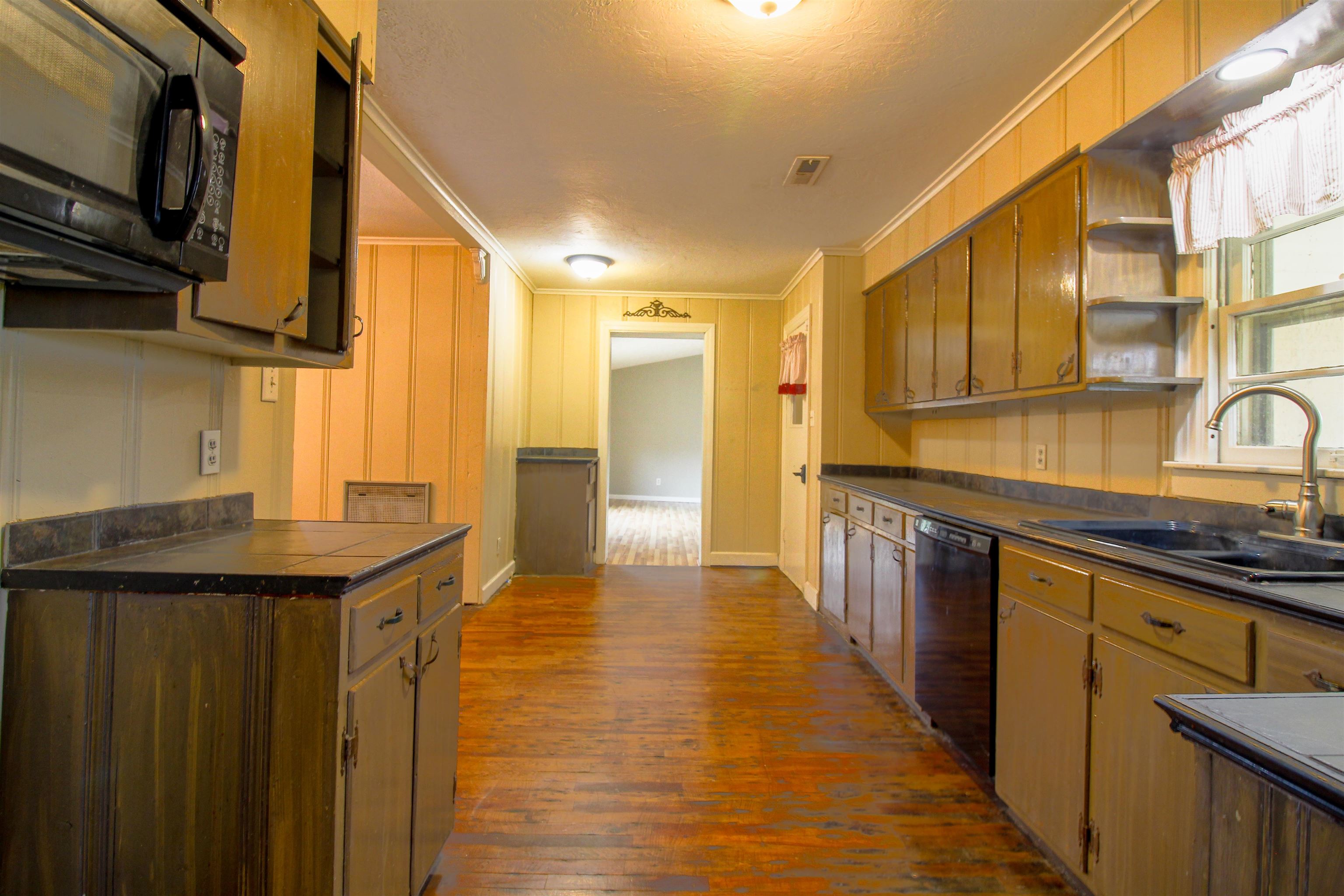 4075 Arp Central Road Ripley, TN 38063 - Photo 6 of 37 Kitchen featuring black appliances, open shelves, crown molding, dark wood-type flooring, and a textured ceiling
