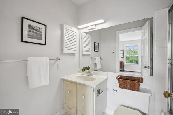 a bathroom with a sink a mirror a toilet and a window