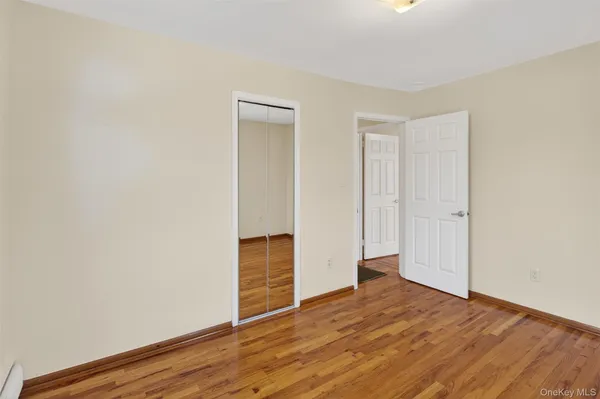 a view of an empty room with wooden floor and closet