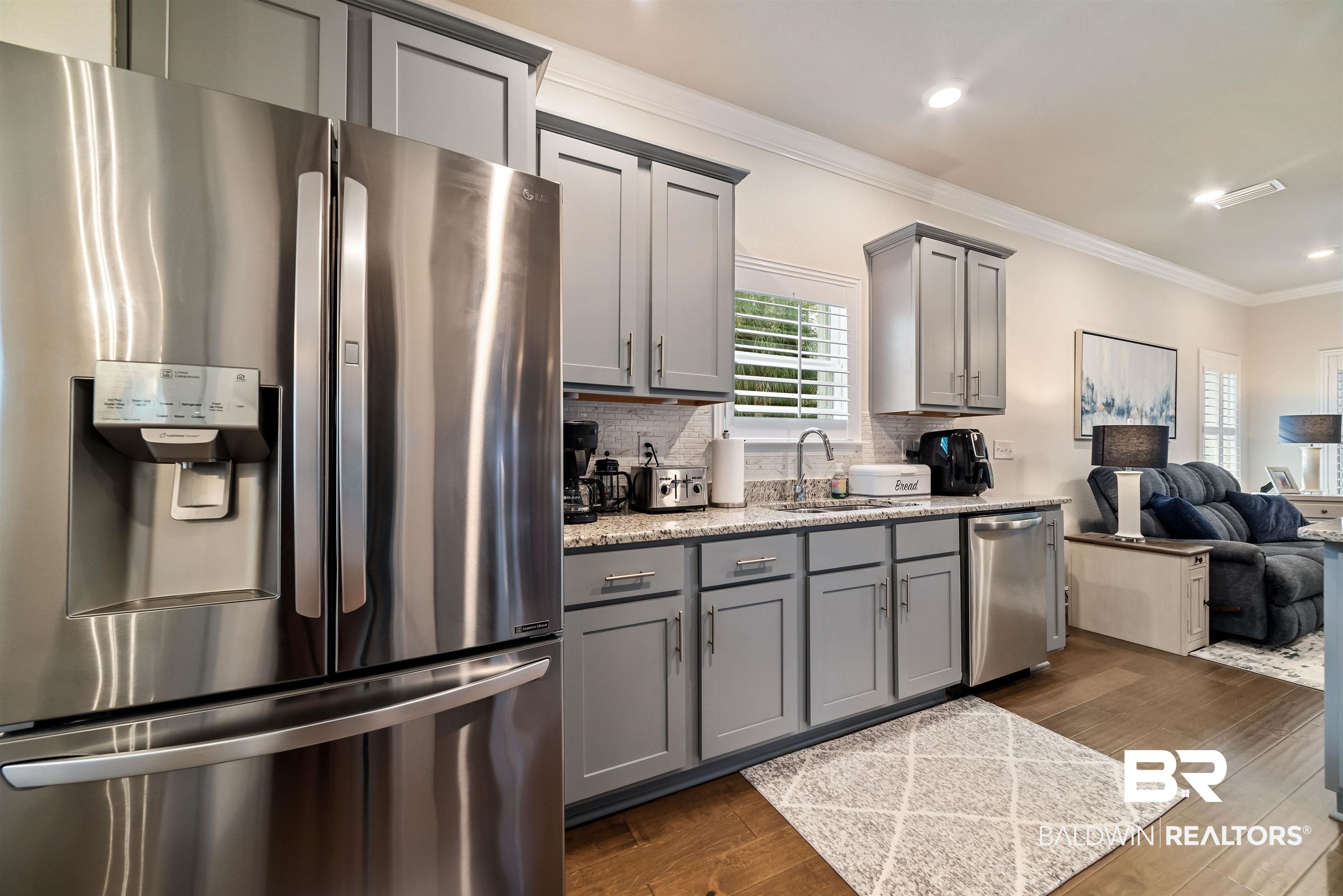1290 Mako Loop Gulf Shores, AL 36542 - Photo 50 of 50 Kitchen featuring appliances with stainless steel finishes, open floor plan, dark wood-style flooring, gray cabinets, and crown molding