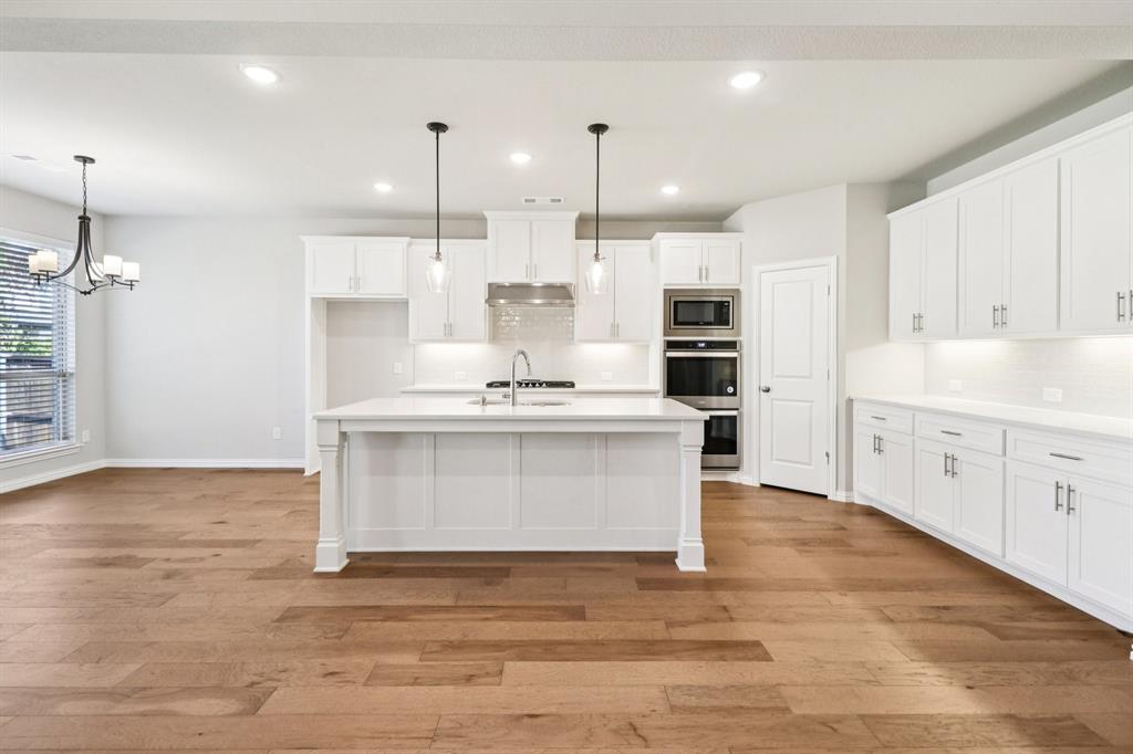 a view of kitchen with granite countertop a stove top oven a sink and white cabinets