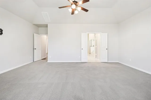 a view of an empty room with chandelier fan and window
