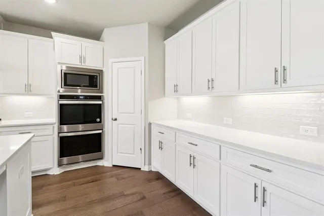 a kitchen with white cabinets and stainless steel appliances