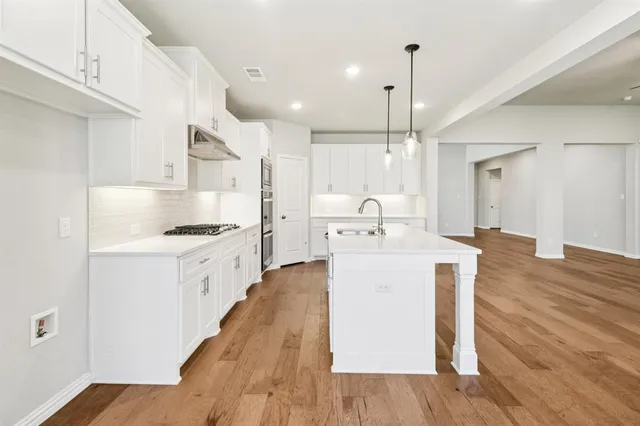 a large kitchen with a lot of counter space and wooden floor