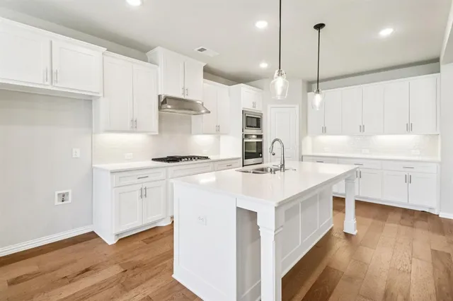 a kitchen with kitchen island a sink stainless steel appliances and cabinets