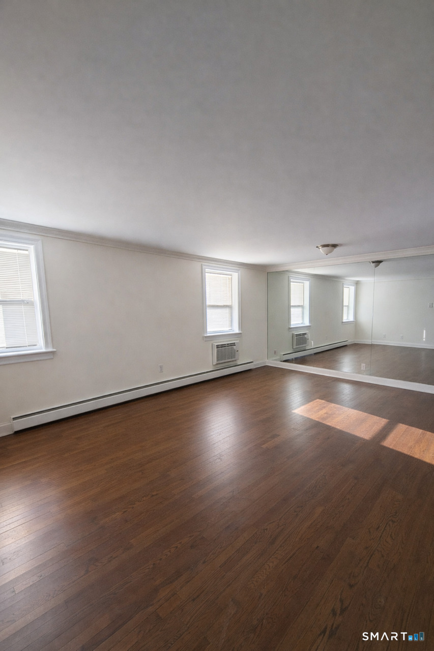 391 Reef Road, Unit 1A Fairfield, CT 06824 - Photo 23 of 24 an empty room with wooden floor and windows