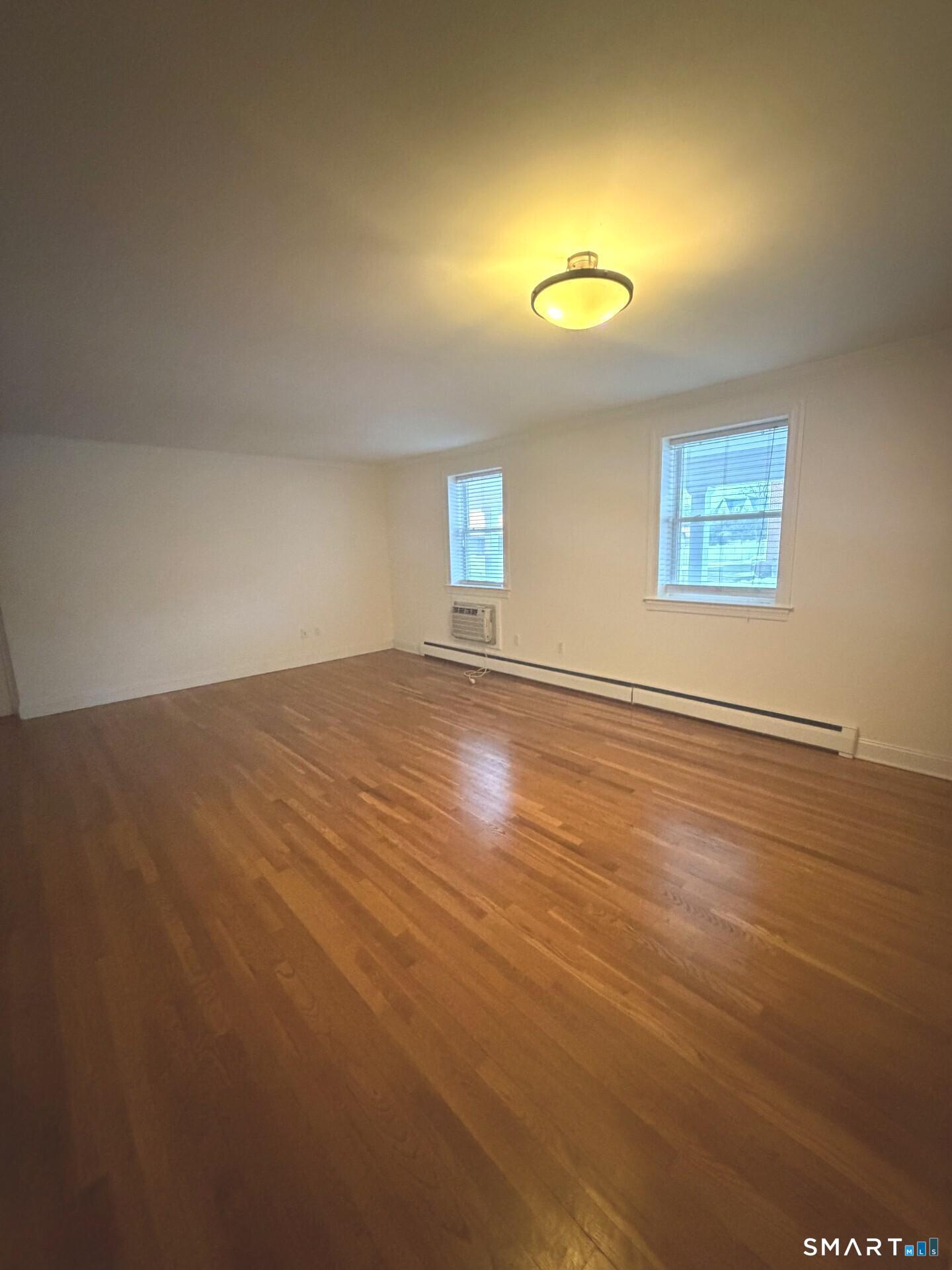 391 Reef Road, Unit 1A Fairfield, CT 06824 - Photo 3 of 24 an empty room with wooden floor and windows