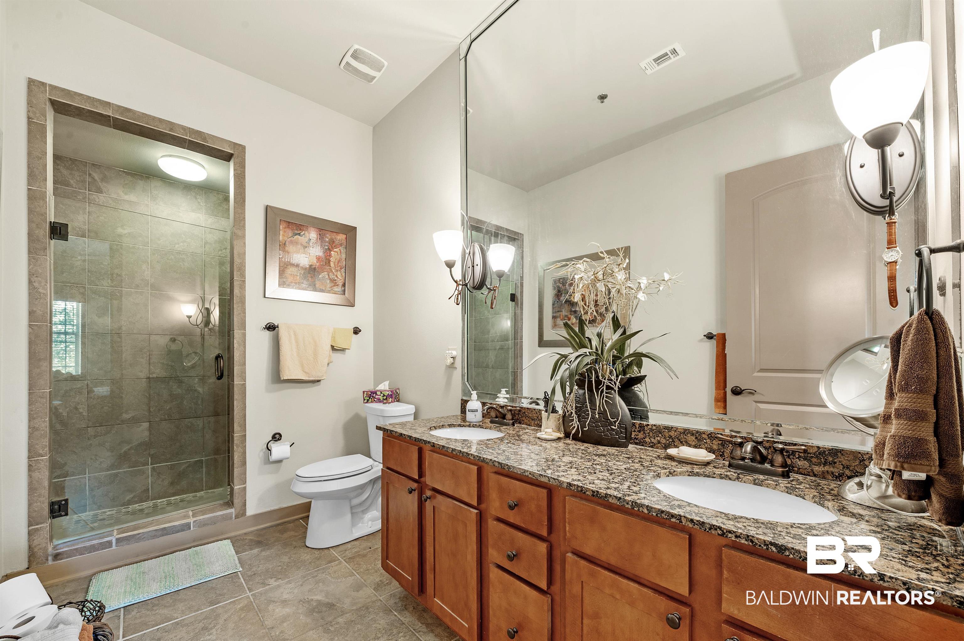 1430 Regency Road, Unit A301 Gulf Shores, AL 36542 - Photo 25 of 47 Bathroom featuring a shower with door, tile patterned flooring, toilet, vanity, and a chandelier