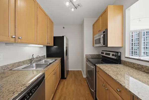 a kitchen with granite countertop stainless steel appliances a sink stove and refrigerator
