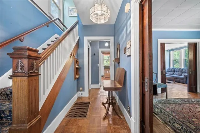 a view of a hallway to a livingroom with wooden floor and furniture