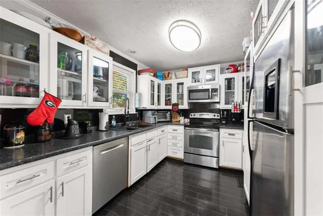 a kitchen with stainless steel appliances granite countertop a stove top oven a sink dishwasher and white cabinets with wooden floor
