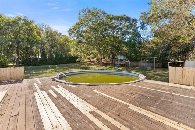 a view of swimming pool with seating space and trees in the background