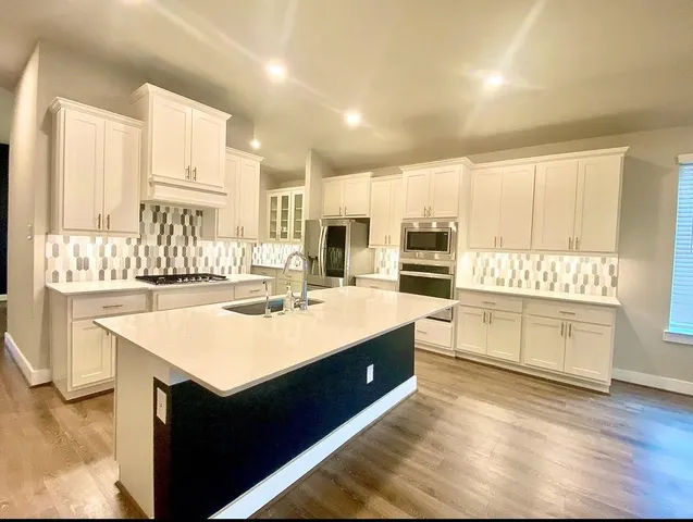 a large white kitchen with stainless steel appliances