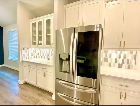 a kitchen with stainless steel appliances a refrigerator and white cabinets