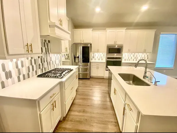 a large kitchen with kitchen island a sink dishwasher a stove and a dining table with wooden floor