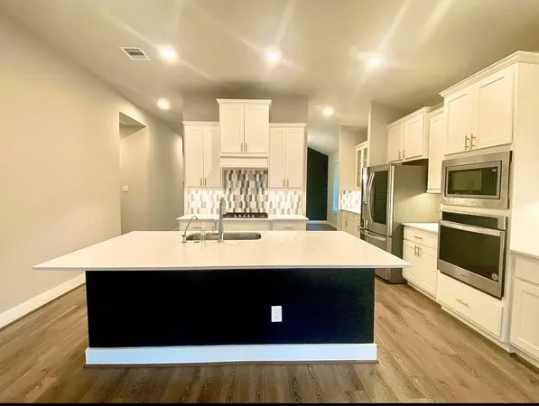 a large kitchen with kitchen island a sink a stove and a refrigerator with wooden floor