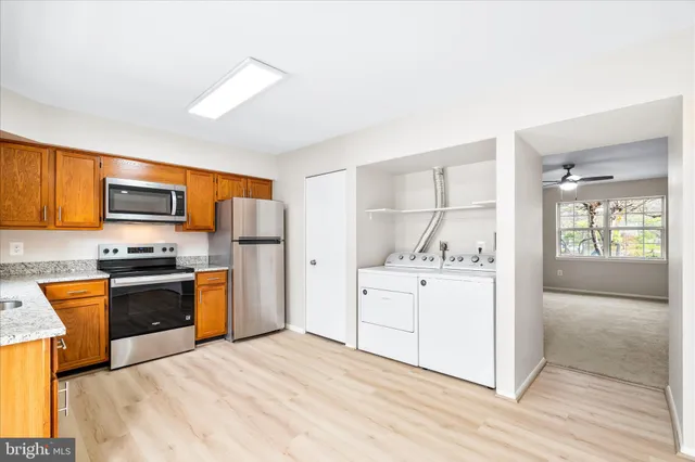 a kitchen with stainless steel appliances granite countertop a stove top oven a refrigerator a sink and dishwasher with wooden floor