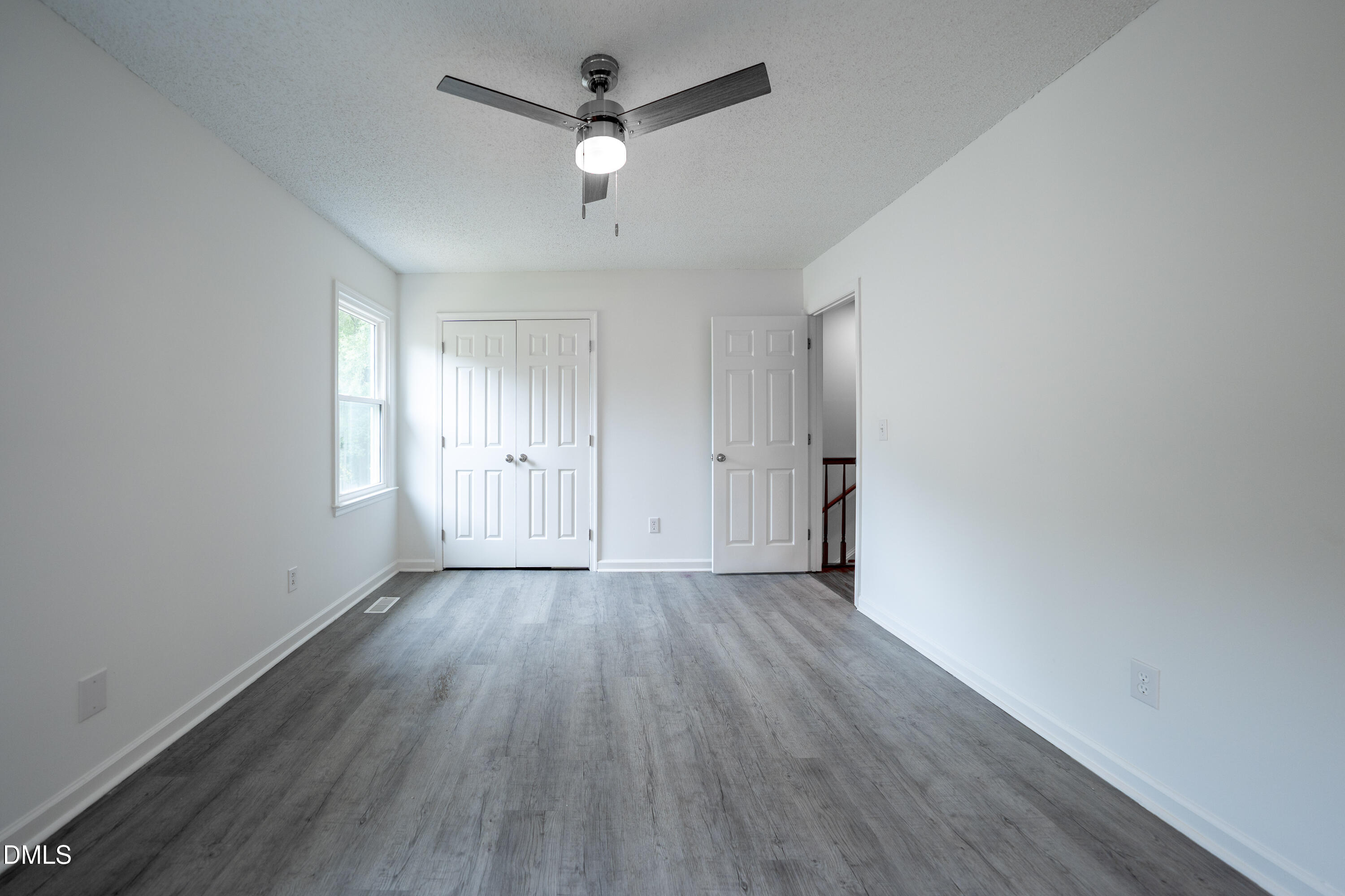6901 Saxby Court Raleigh, NC 27613 - Photo 16 of 36 an empty room with wooden floor ceiling fan and windows