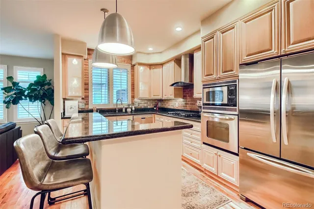 a kitchen with stainless steel appliances granite countertop a stove a sink dishwasher a refrigerator and cabinets with wooden floor