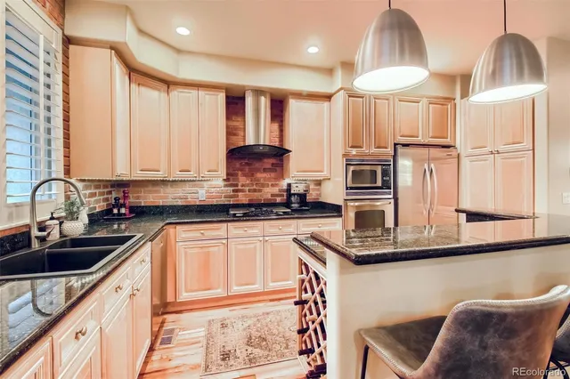 a kitchen with stainless steel appliances granite countertop a sink a stove and a refrigerator