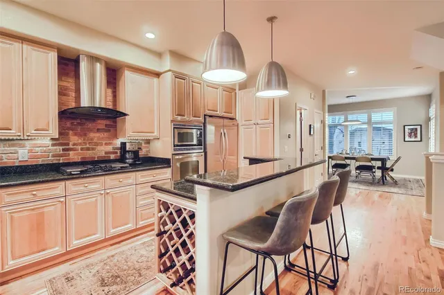 a kitchen with stainless steel appliances granite countertop a kitchen island a stove and a wooden floors