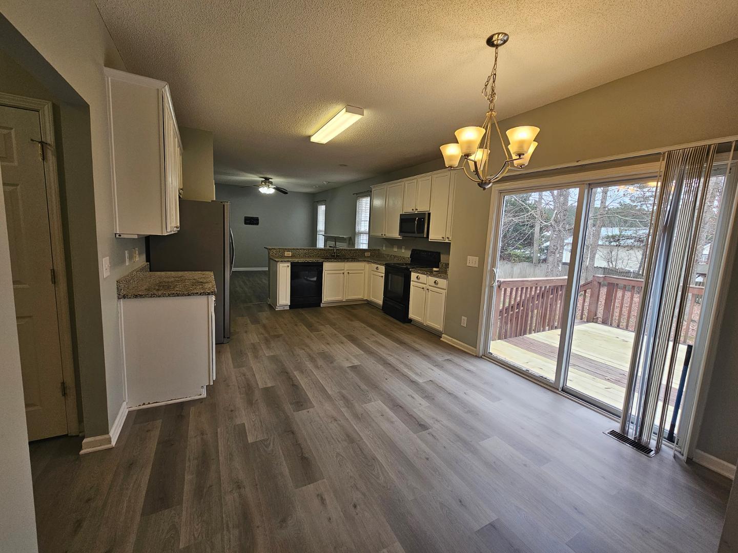 2341 Brasstown Lane Apex, NC 27502 - Photo 7 of 24 a view of a kitchen with granite countertop wooden floor stainless steel appliances and a chandelier