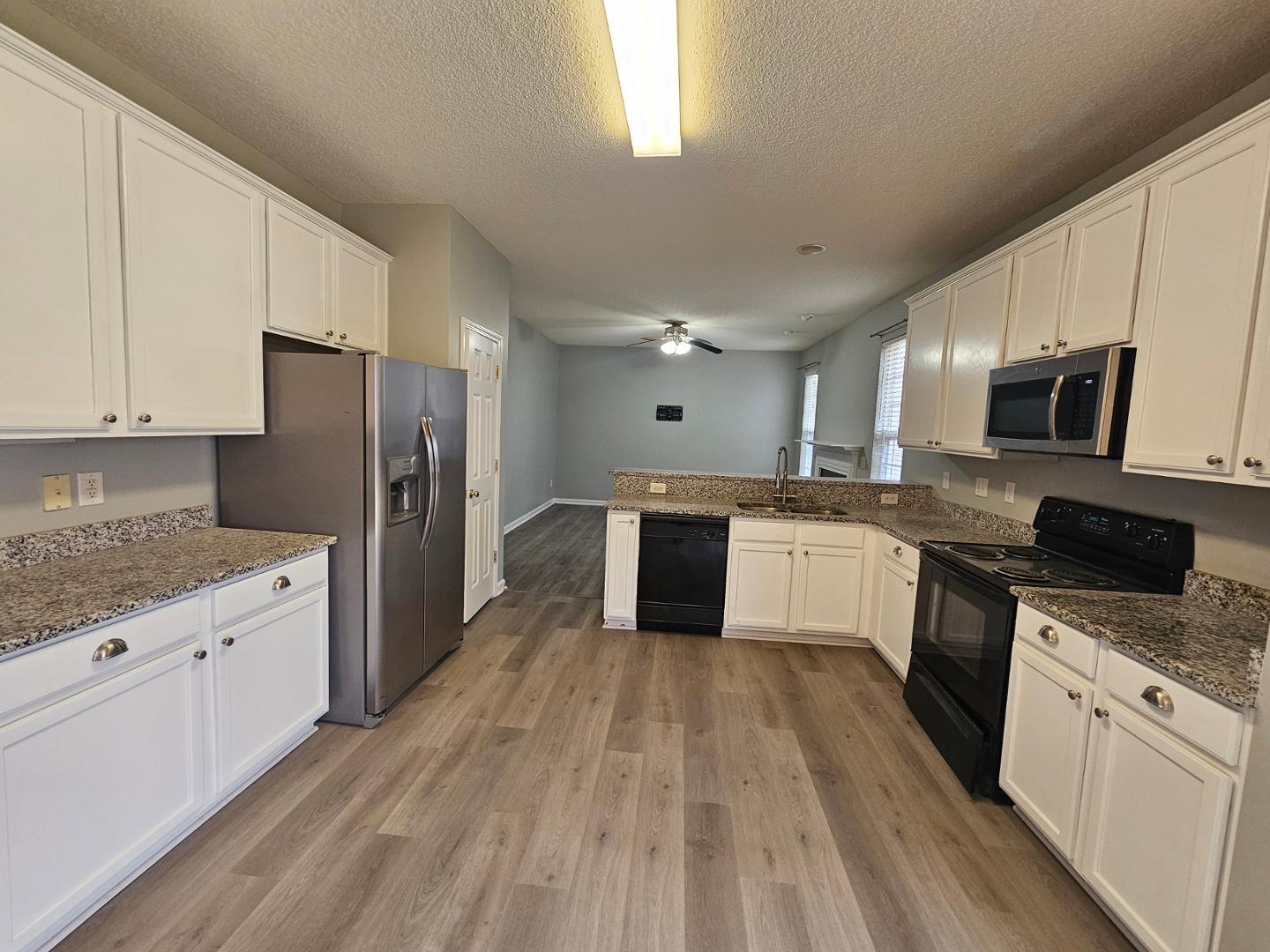 2341 Brasstown Lane Apex, NC 27502 - Photo 8 of 24 a large kitchen with a stove a sink dishwasher a refrigerator and white cabinets with wooden floor