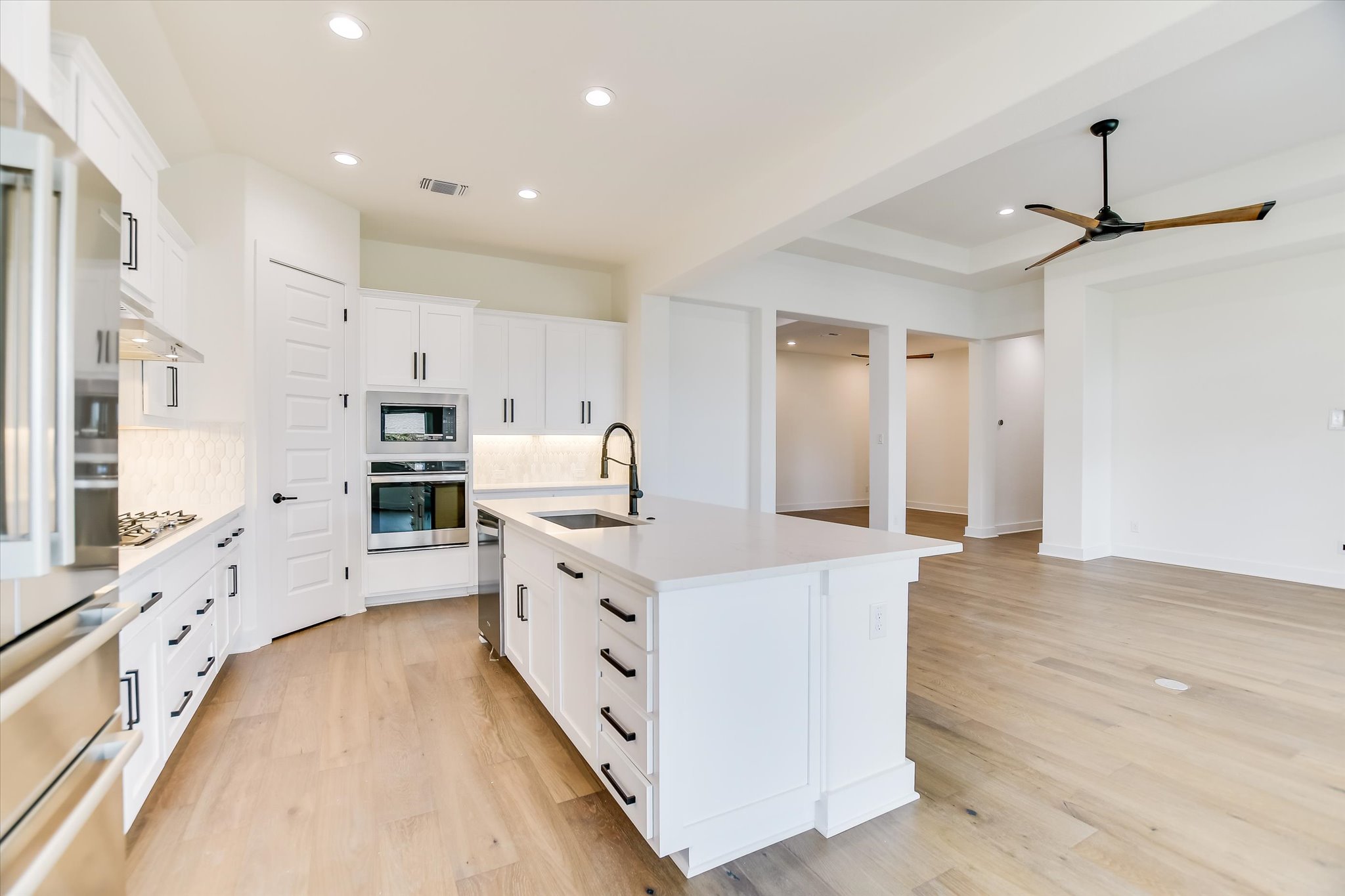 4300 Allenbrook Drive Pflugerville, TX 78660 - Photo 8 of 40 a large kitchen with stainless steel appliances a stove a sink a refrigerator and white cabinets with wooden floor