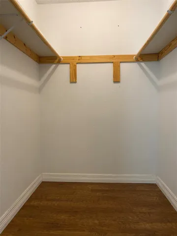 an empty room with wooden floor chandelier fan and windows
