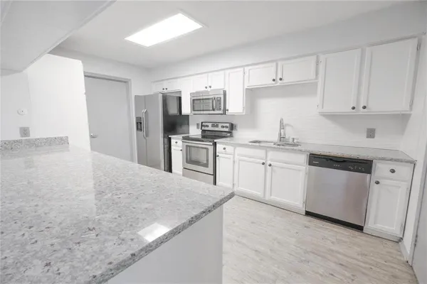 a view of a big room with wooden floor and windows