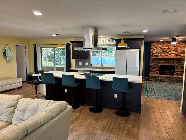 a living room with stainless steel appliances kitchen island granite countertop furniture a large window and a fireplace