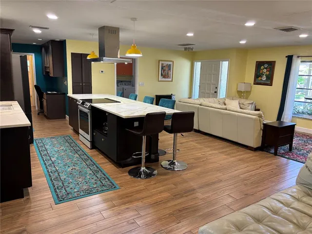 a view of kitchen with stainless steel appliances granite countertop sink stove and wooden floor
