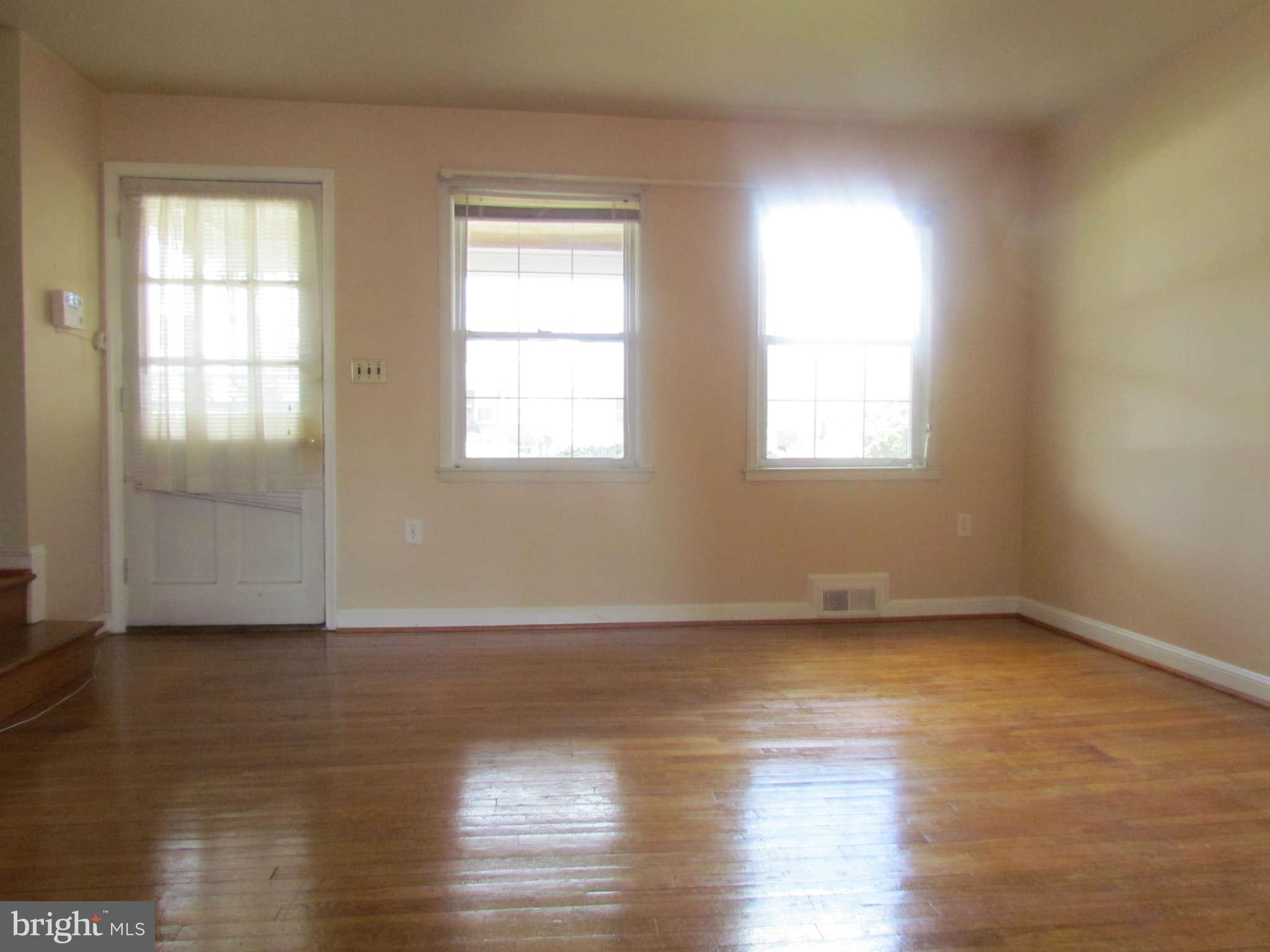1327 Silverthorne Road Baltimore, MD 21239 - Photo 2 of 16 an empty room with wooden floor and windows