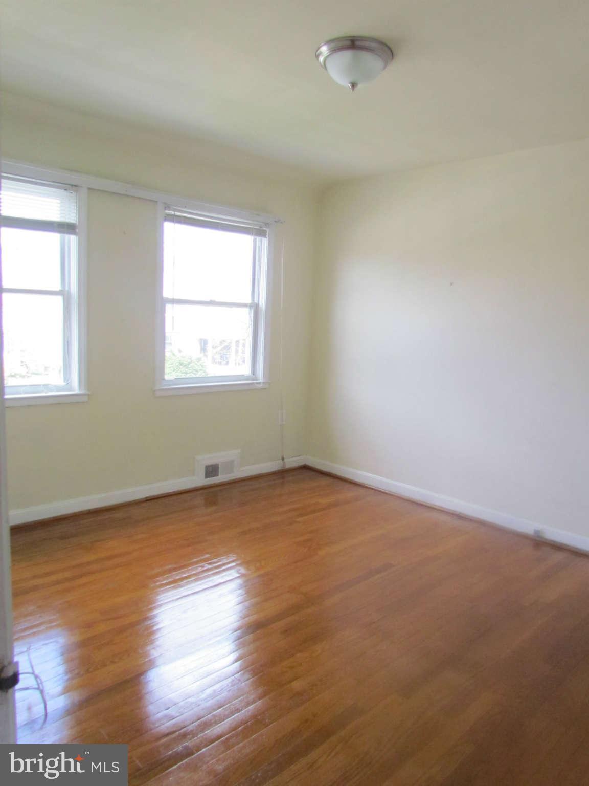 1327 Silverthorne Road Baltimore, MD 21239 - Photo 14 of 16 an empty room with wooden floor and windows